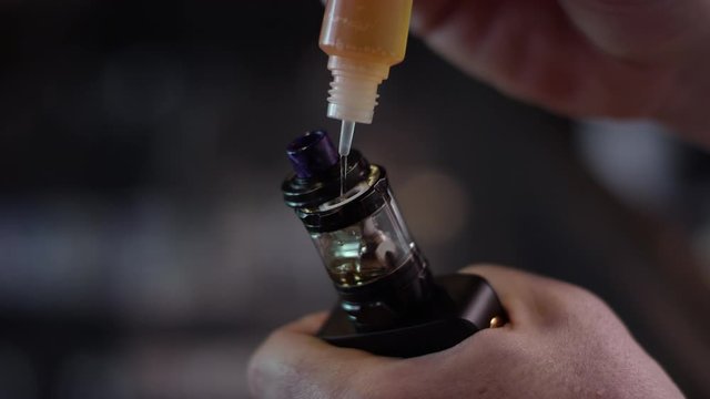 Close-up of liquid getting poured into a vape atomizer for smoking