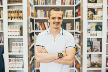 Smiling man looking in camera with bookshelfs behind in the library