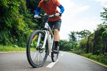 Fototapeta premium Woman cyclist riding mountain bike on tropical forest trail