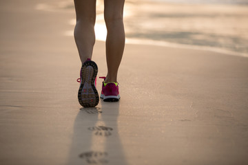 Young fitness female runner legs running at beach