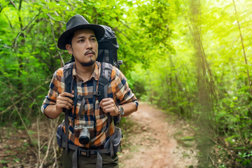 man traveler with backpack looking to the side walking in the forest
