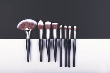 Set of makeup brushes on black and grey color block background.