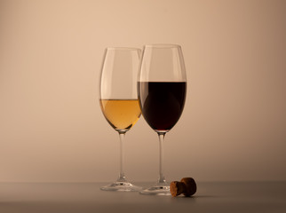 Two wineglass one half full of white wine one red black bottle cork