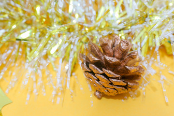 Christmas decorations fir cones gift boxes tinsel on yellow background macro