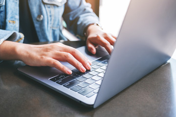 Closeup image of a woman working and typing on laptop computer on the table