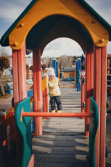 A little girl playing on the Playground of the children's town. a small child rides down the hill, on the carousel, climbs the ropes. Entertainment industry concept, family day, children's parks