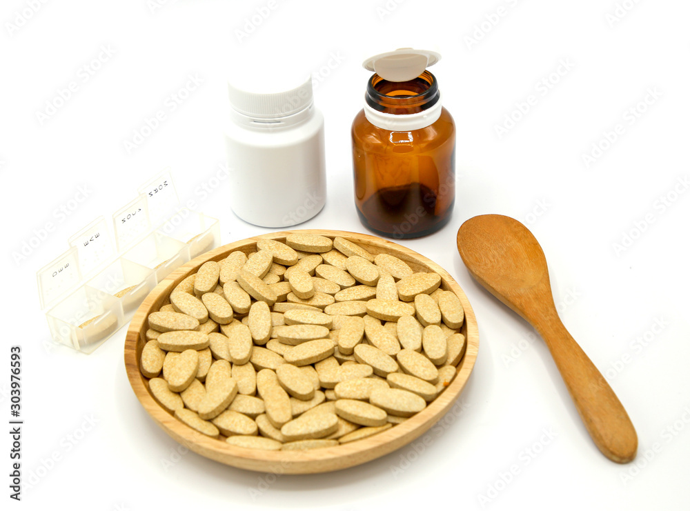 Wall mural pills of vitamin c in wooden bowl isolated on white background