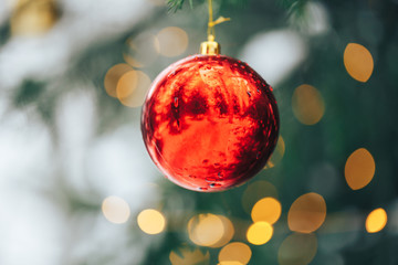 Red christmas ball hanging on branch on sruce tree outdoor, snow, winter, with decorations.