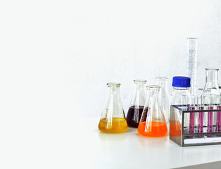 Group of glass bottle, test tube on rack with liquid water, conical flasks and microscope on white background, Science laboratory research concept.