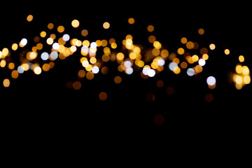 Golden glitter bokeh lights on black background, unfocused. Holiday time.