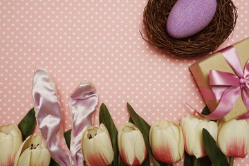 Easter egg with gift box and tulip flower on pink polka dot background