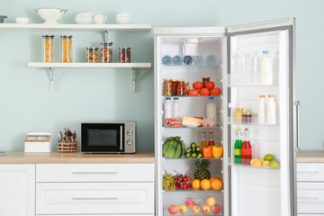 Open big fridge with products in kitchen