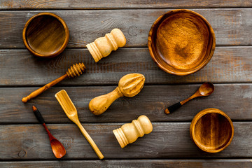 Set of rustic wooden tableware - bowls and utensils on dark wooden background top view pattern