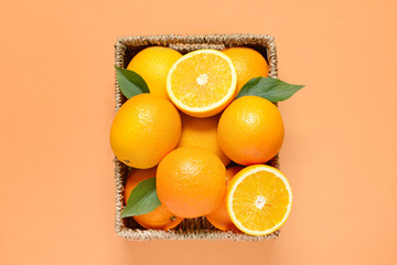 Basket with fresh oranges on color background