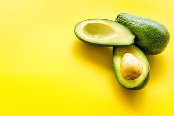 Avocado - ripe and bright, cutted in half - on yellow background closeup copy space