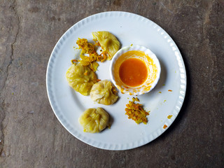 hot momos with red chutny put in a white plate on stone background