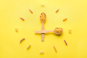 Composition with spoons and uncooked pasta on color background