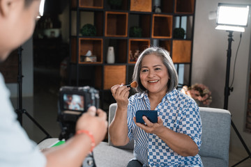 Old women making a video for her blog on cosmetics using digital camera