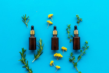 Aromatherapy. Essential oils near herbs and leaves on blue background top view
