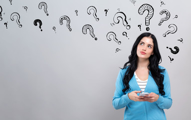 Question marks with thoughtful young woman holding a smartphone