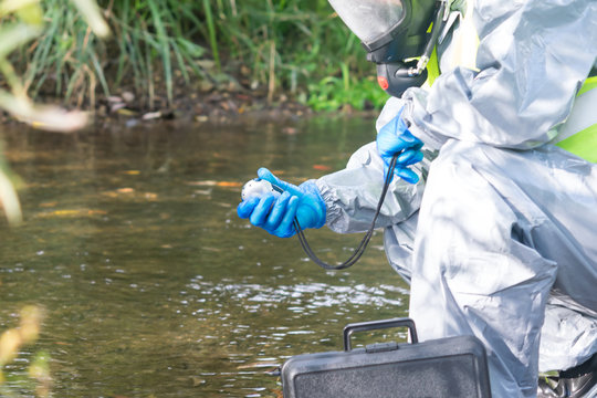 specialist in a protective suit and mask, is measuring the device on the pond, holding it in his hands, close-up