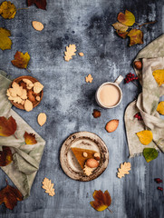 traditional pumpkin pie decorated with leaves shaped cookies on shabby blue background with coffee and textile