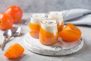 Chia pudding with persimmon. Autumn or winter dessert. light gray background. Healthy vegan, vegetarian breakfast table.
