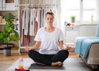 Schilderijen op glas Jonge vrouw doet yoga oefening binnenshuis thuis, mediteren. © Halfpoint