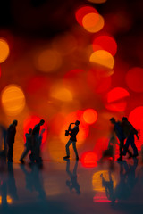 Miniature toy - Man blowing saxophone on the street with colorful bokeh lights among busy commuters crowd with colorful bokeh lights.