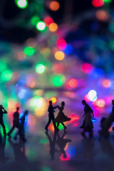 Obraz na płótnie Canvas Miniature toy - A couple dancing on the street together among busy commuters crowd with colorful bokeh lights, happiness concept.