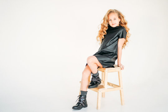 Beauty fashion portrait of smiling curly hair tween girl in black leather dress and on white background