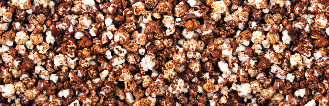Background and texture of chocolate popcorn. Panorama. View from above. Banner.