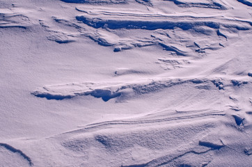 The surface of the snow cover in the light of the sun, with abstract patterns formed by the wind, a copy space, close-up, toned.