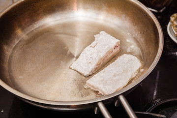 frying fish in a frying pan at home