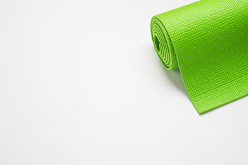 Green Yoga mat for Yoga, Pilates exercise at home or gym rolled on white background with copy space for your text
