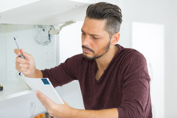 Fototapeta premium man reading the instructions for cabinet door assemblng