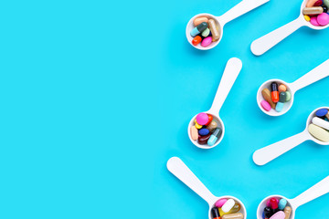 Colorful medicine pills, tablets and capsules on blue background.