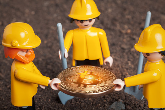 lego miner figures holding big glowing bitcoin  in hands