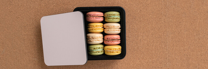 Macarons selection of flavors in gift box top view brown background.