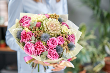 European floral shop. Beautiful bouquet of mixed flowers in womans hands. the work of the florist at a flower shop. Delivery fresh cut flower.