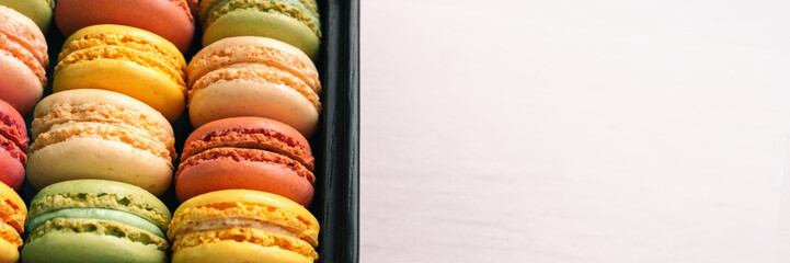 Fototapeta premium Macarons giftbox top view panoramic banner white wooden background.