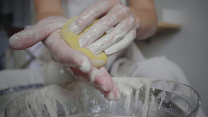 Closeup of female potter wipes her hands from clay with a wet sponge. Potter washes her hands after molding clay