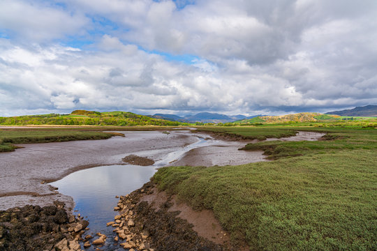 A small branch of the River Esk with clouds over Lake District in the background, seen near Newbiggin, Cumbria, England, UK
