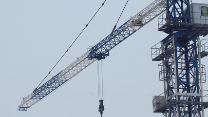 Naklejka premium Tower crane lifts cargo onto a building under construction