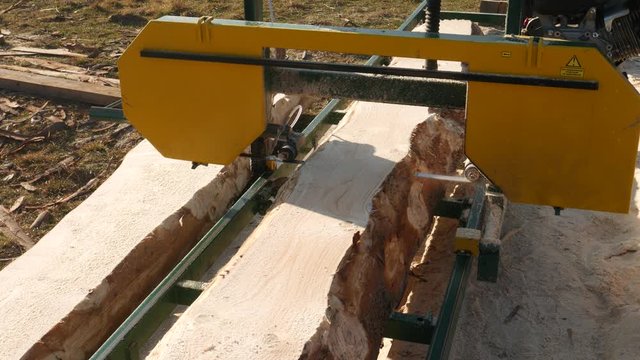 A close up view of an sawmill machine, processing a log of wood at a wood processing mill. .