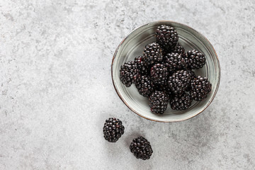 Blackberry in a plate on a gray stone background