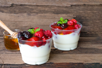 Fruit yogurt has strawberry, raspberry, blueberry, canberry and honey greek white clean In bowl on a wooden background.