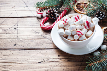 A Cup of hot chocolate with marshmallows. Christmas tree and decorations, cane caramel and oranges nuts Wooden background copy space.