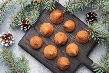 Obraz na płótnie Canvas Delicious chocolate truffles sprinkled with cocoa powder on a wooden stand. Christmas tree scenery concept.