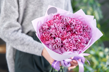 Violet mono bouquet of carnation in womans hands. European floral shop. the work of the florist at...